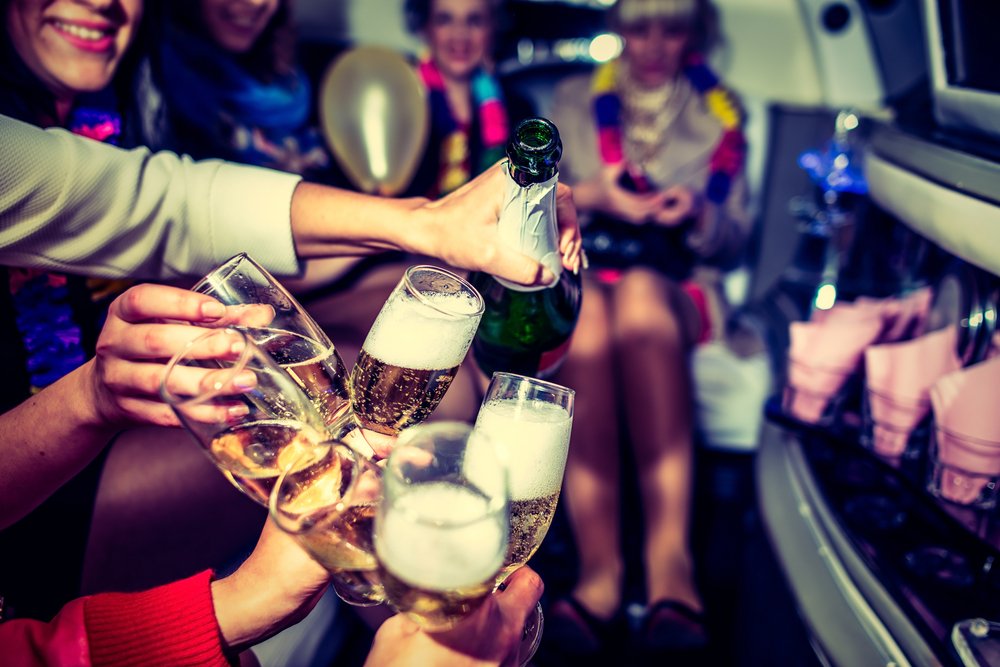 group pouring champagne inside a stretch limo