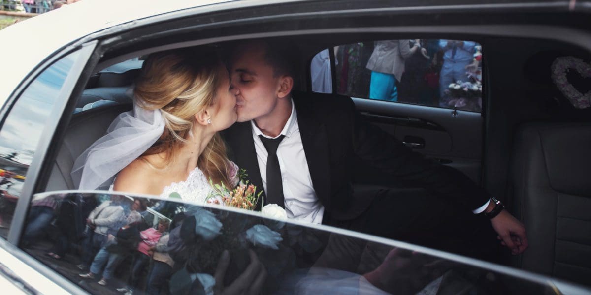 Happy romantic newlyweds kissing in wedding limo